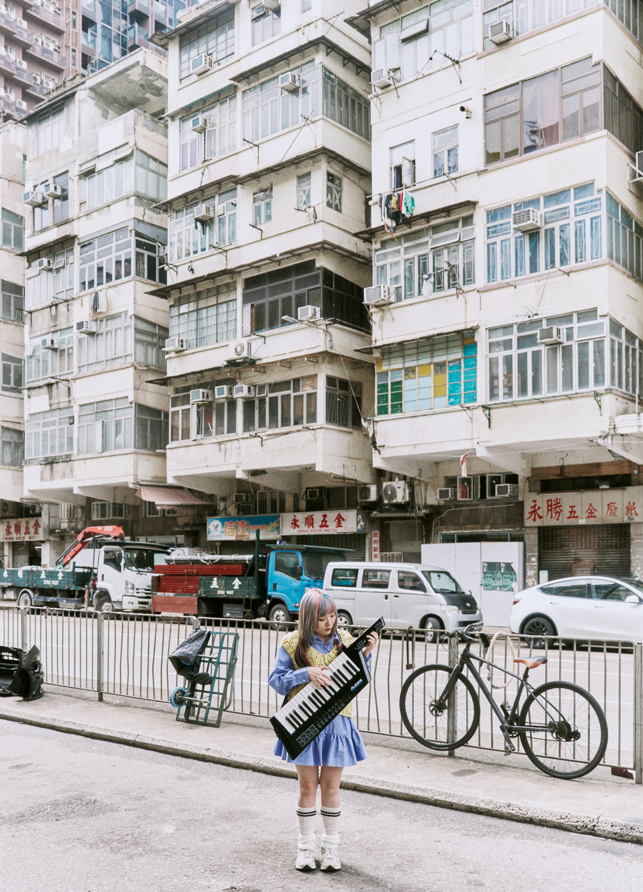 Kylie with her keytar beneath Hong Kong tenement buildings