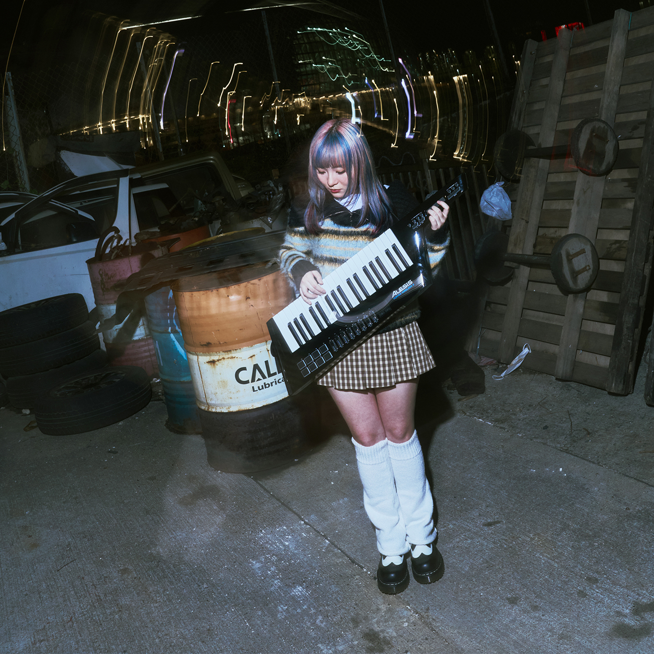 Kylie playing keytar among a Hong Kong workshop’s barrels and night lights