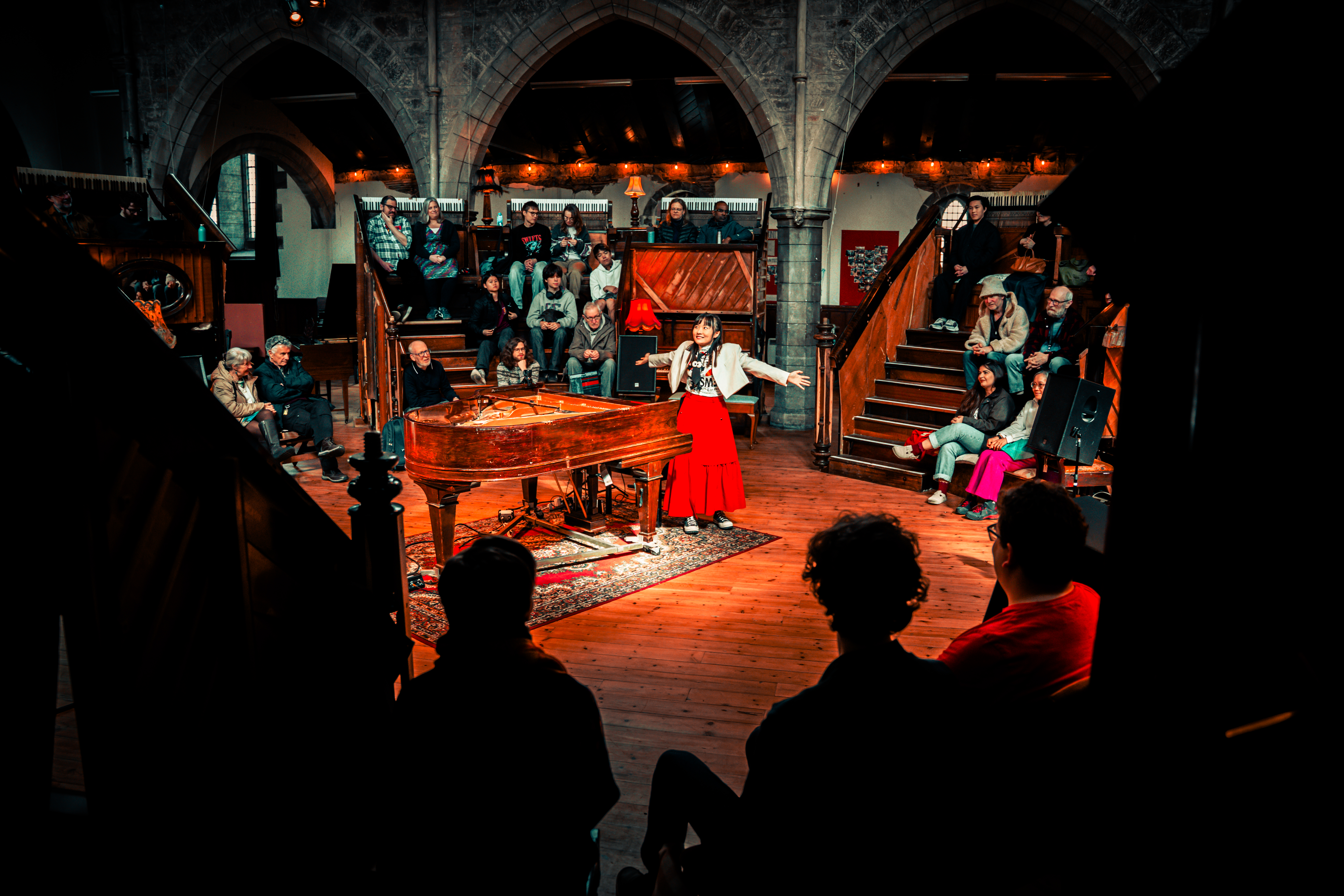 TC.KYLIE beside the grand piano, surrounded by the audience at Pianodrome, Edinburgh